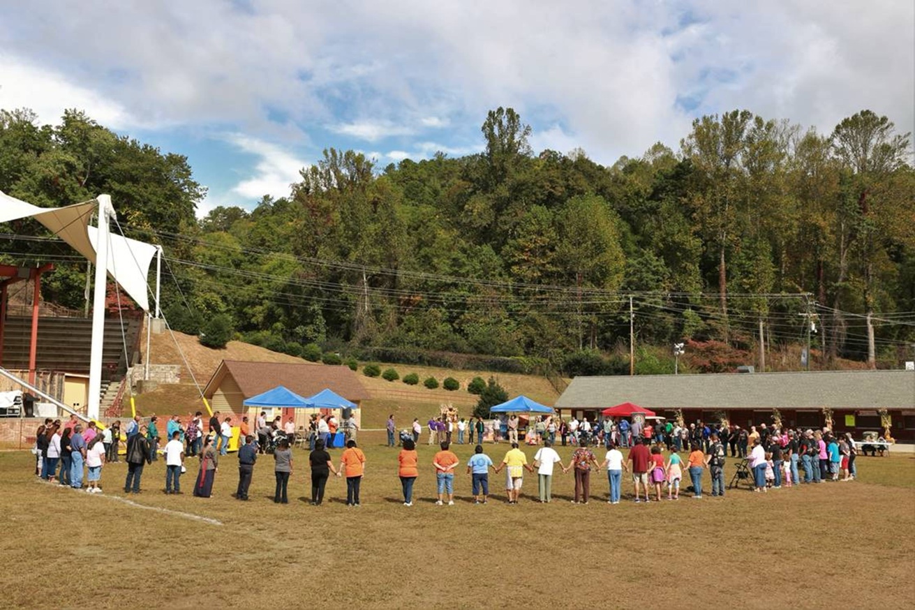 Annual prayer circle started by Chief Lambert, community holding hands on the field