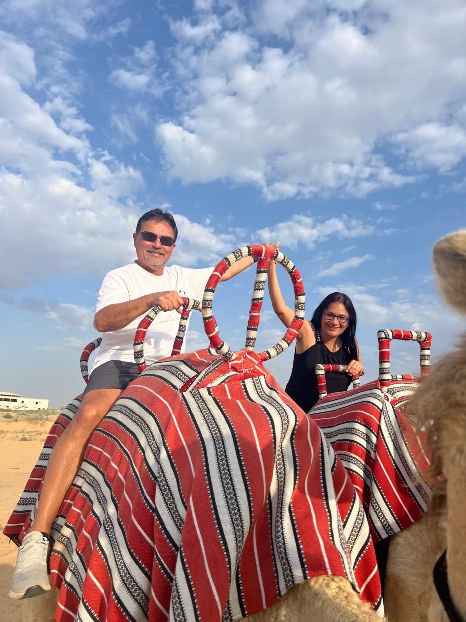 Patrick and Cyndi Lambert riding camels in the Dubai desert