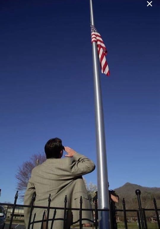 Chief Lambert saluting the flag at half-staff on the Qualla Boundary